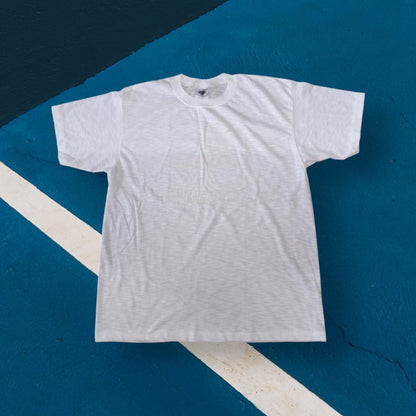 White linen cotton T-shirt laid flat on a blue and white geometric background